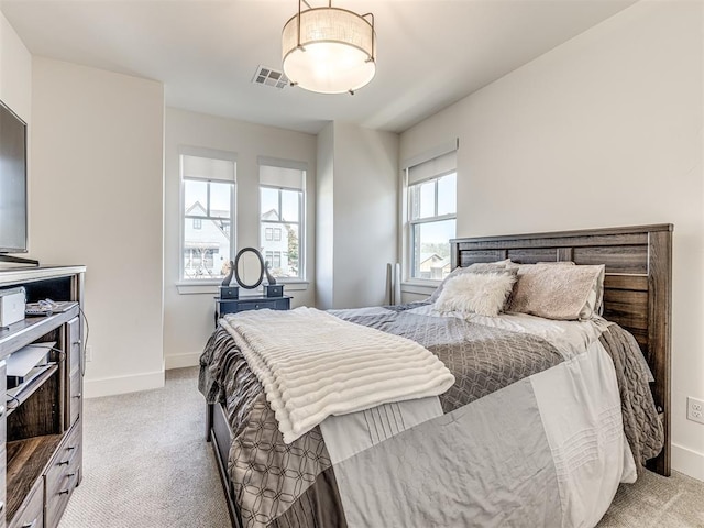 bedroom featuring visible vents, light carpet, and baseboards