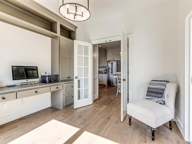 home office featuring light wood-style floors, built in study area, and an inviting chandelier