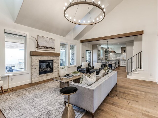 7308 Sunset Sail Ave, Edmond, OK 73034 - living area featuring a stone fireplace, baseboards, light wood finished floors, a notable chandelier, and stairs
