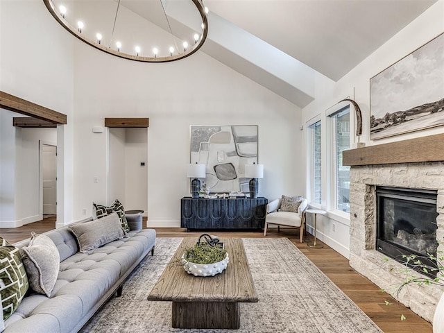 7308 Sunset Sail Ave, Edmond, OK 73034 - living area featuring a stone fireplace, wood finished floors, high vaulted ceiling, baseboards, and an inviting chandelier