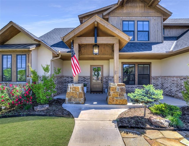7308 Sunset Sail Ave, Edmond, OK 73034 - property entrance with covered porch, brick siding, a shingled roof, and stucco siding
