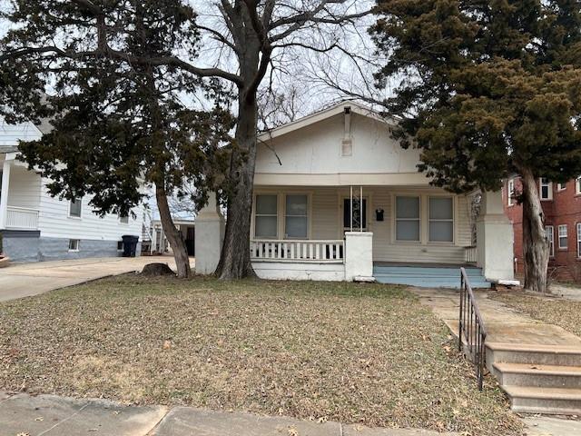 bungalow-style home featuring a front yard and covered porch