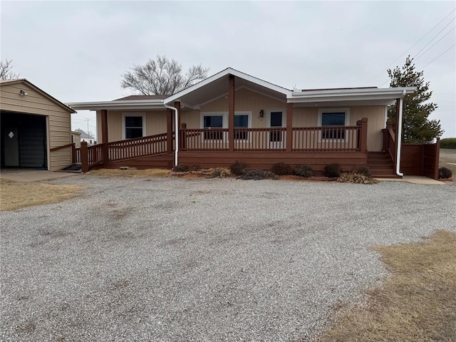 single story home with a garage, an outdoor structure, and a porch