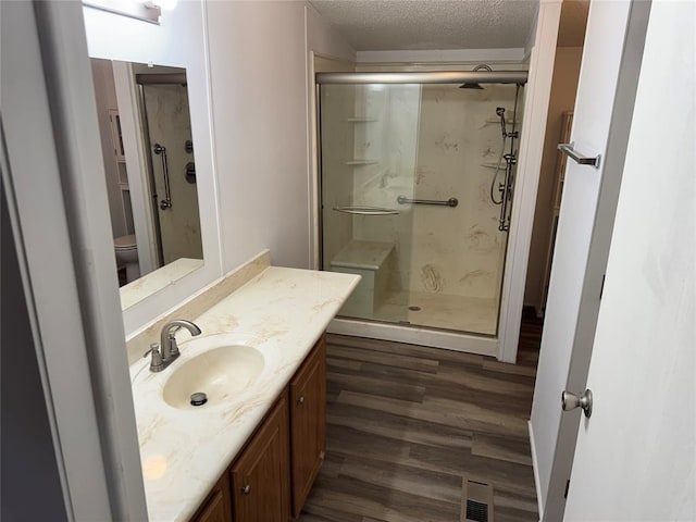 bathroom with an enclosed shower, toilet, a textured ceiling, vanity, and hardwood / wood-style floors