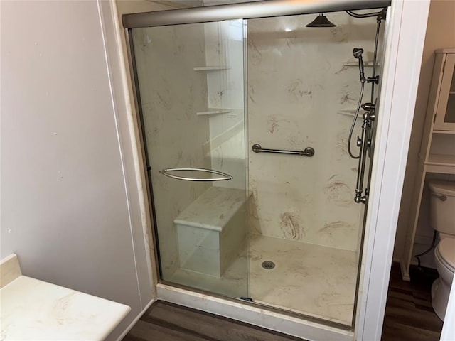 bathroom featuring hardwood / wood-style flooring, toilet, and a shower with shower door