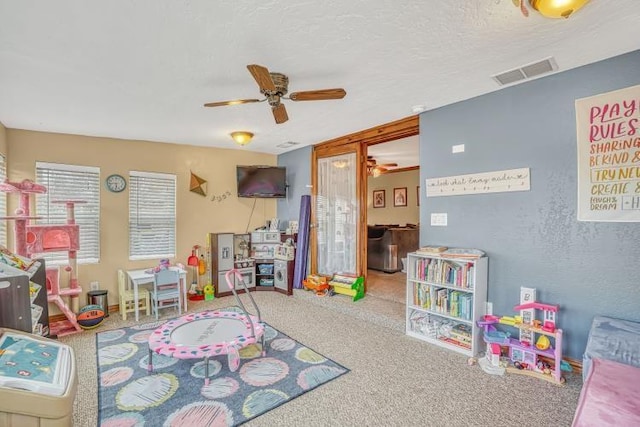 game room with ceiling fan, carpet, and a textured ceiling