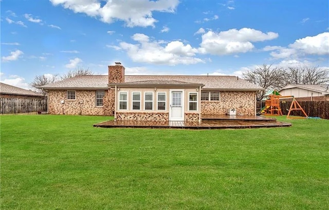 rear view of property with a yard and a playground