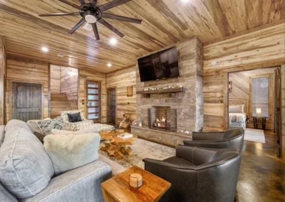 living room with a ceiling fan, wood ceiling, wood walls, a fireplace, and recessed lighting