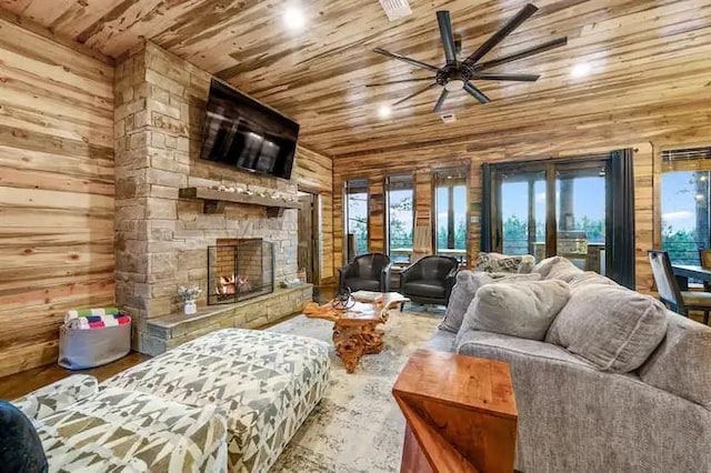 living room with lofted ceiling, wooden ceiling, a stone fireplace, and wood walls