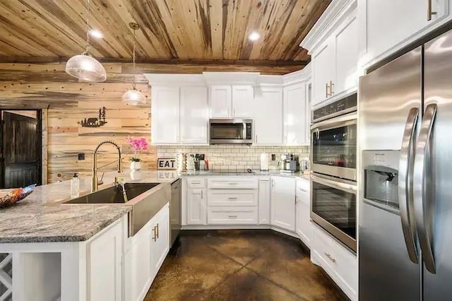 kitchen featuring stainless steel appliances, white cabinets, decorative light fixtures, and a sink