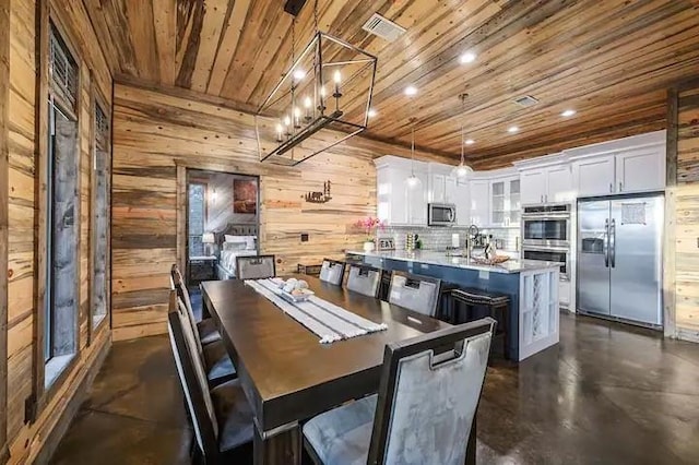 dining room with finished concrete floors, recessed lighting, wood ceiling, and wooden walls