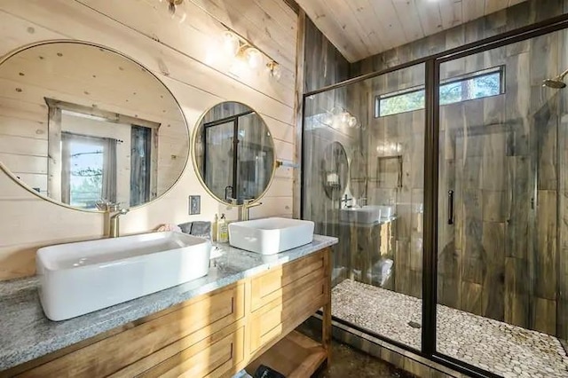 full bath with wooden walls, a sink, a shower stall, and double vanity