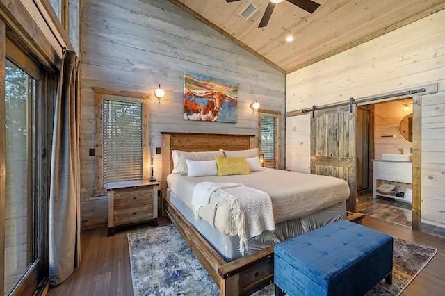 bedroom featuring a barn door, dark wood finished floors, wooden ceiling, wood walls, and high vaulted ceiling