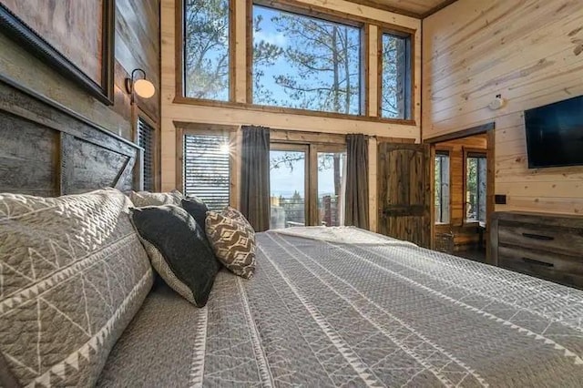 bedroom with access to exterior, wooden walls, and a high ceiling