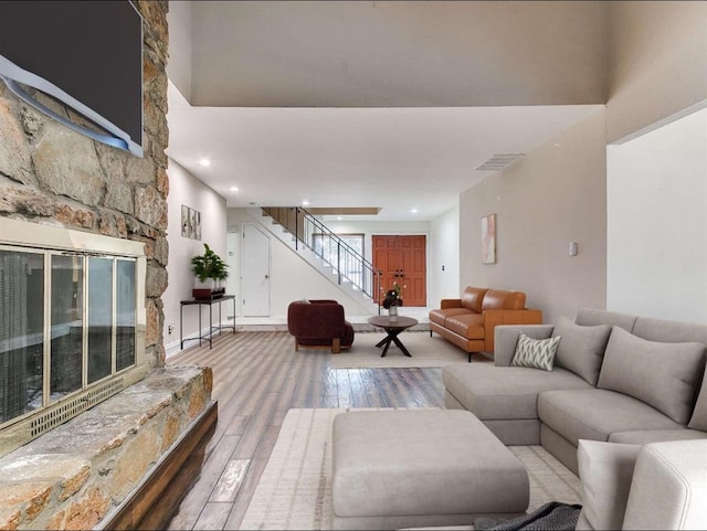 living room with hardwood / wood-style flooring and a stone fireplace