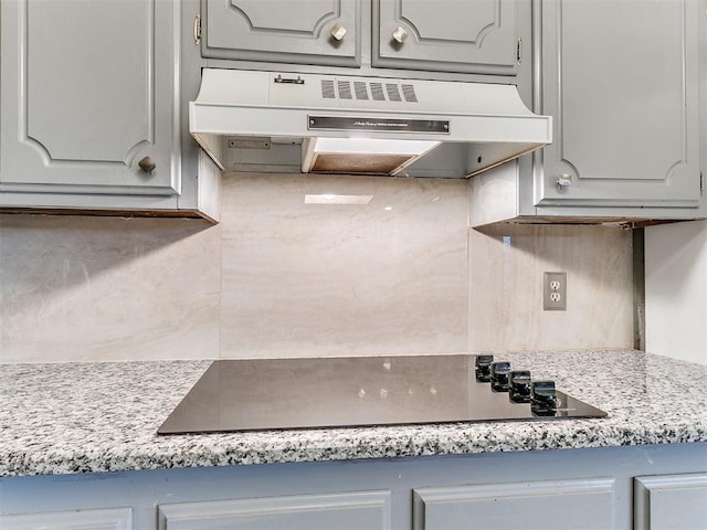 kitchen featuring gray cabinetry, black electric stovetop, and backsplash