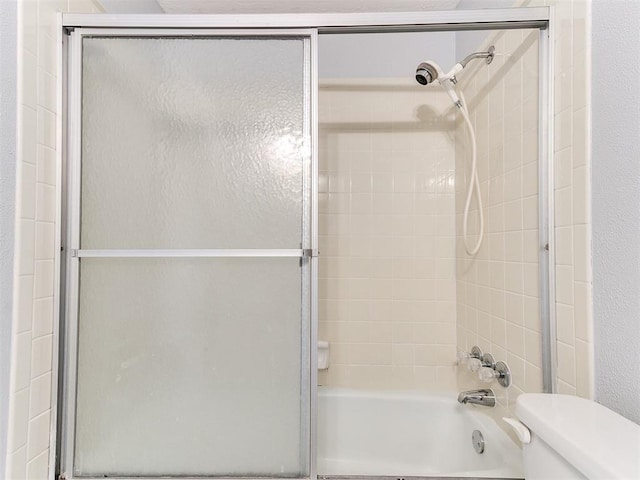 bathroom featuring enclosed tub / shower combo and toilet