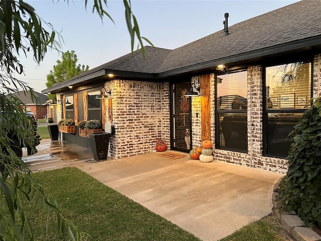 back house at dusk featuring a patio