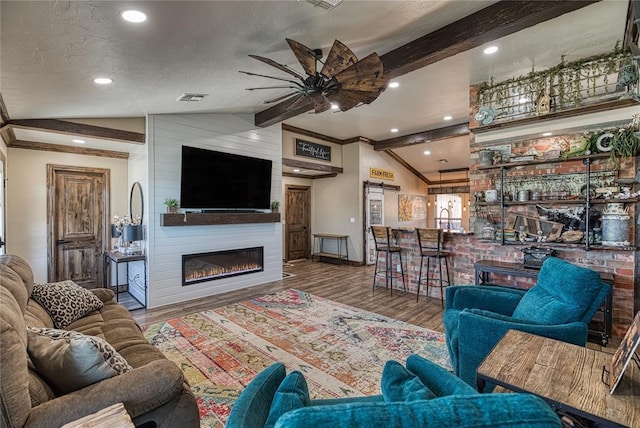 living room with hardwood / wood-style floors, a fireplace, lofted ceiling with beams, and indoor bar