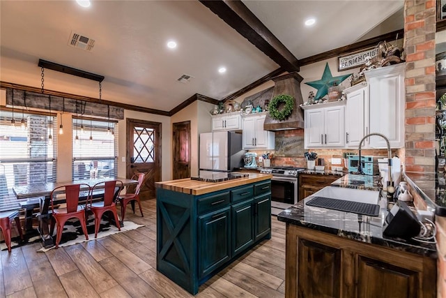 kitchen with wood counters, white cabinetry, a center island, white refrigerator, and stainless steel range with gas cooktop