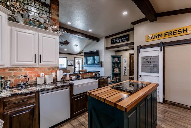 kitchen featuring butcher block countertops, dishwasher, white cabinetry, a kitchen island, and a barn door