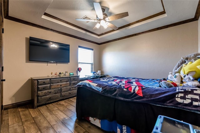 bedroom with ceiling fan, ornamental molding, wood-type flooring, and a tray ceiling