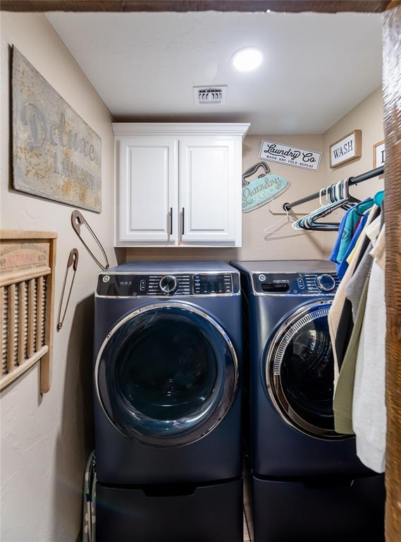 washroom with cabinets and washing machine and clothes dryer