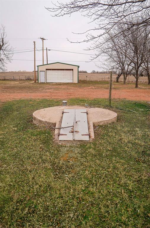 view of storm shelter with a rural view, a lawn, and an outbuilding