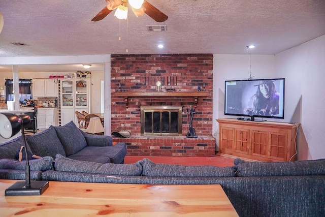 living room featuring a ceiling fan, a fireplace, visible vents, and a textured ceiling