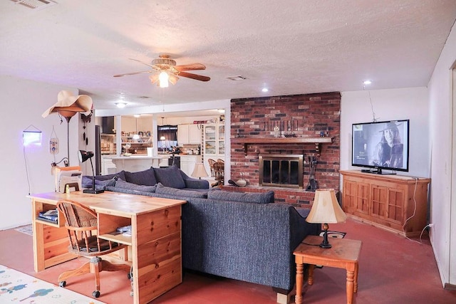 living room with a ceiling fan, a fireplace, visible vents, and a textured ceiling