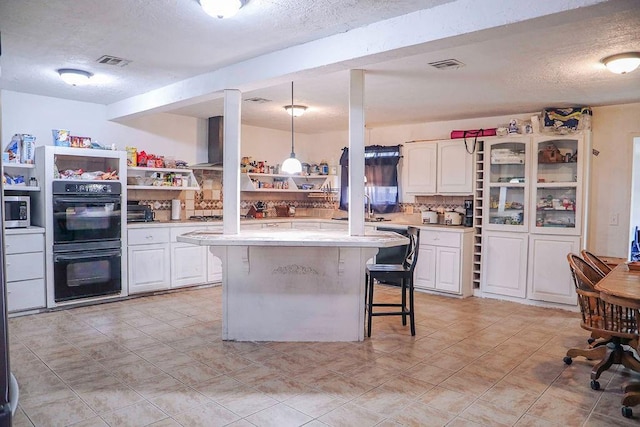 kitchen featuring light countertops, a breakfast bar area, visible vents, and dobule oven black