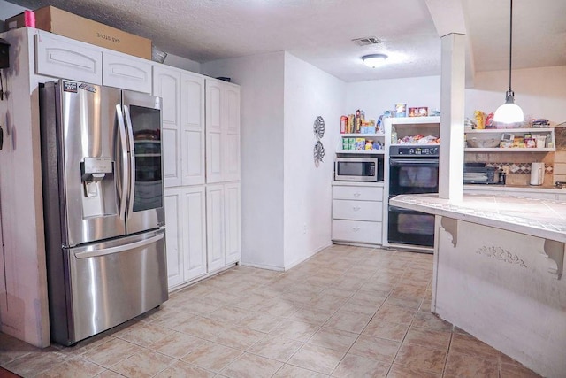 kitchen with visible vents, white cabinets, decorative light fixtures, stainless steel appliances, and a textured ceiling