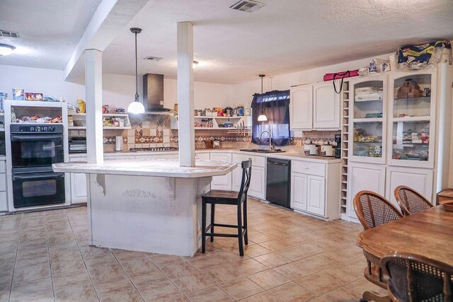 kitchen featuring decorative light fixtures, white cabinets, a kitchen island, wall chimney range hood, and black appliances