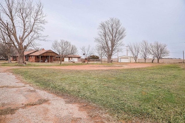 view of yard with dirt driveway and a detached garage