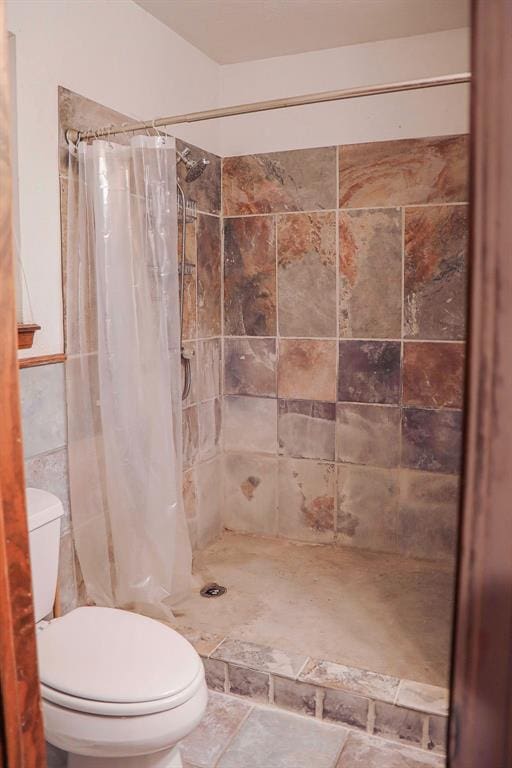 full bath with tile walls, a shower stall, and toilet