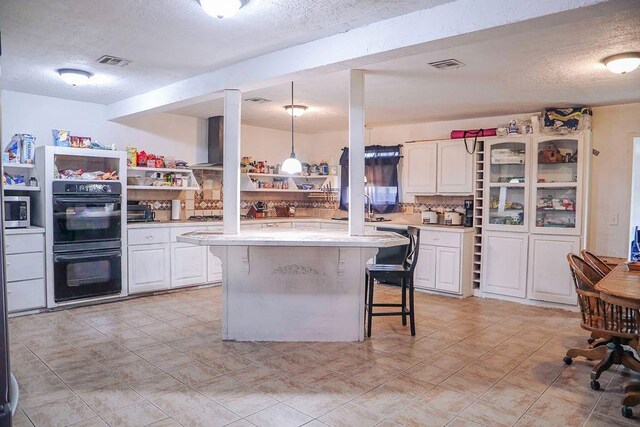 114 N Rambo St, Dill City, OK 73641 - kitchen featuring stainless steel appliances, a textured ceiling, light countertops, a kitchen bar, and open shelves