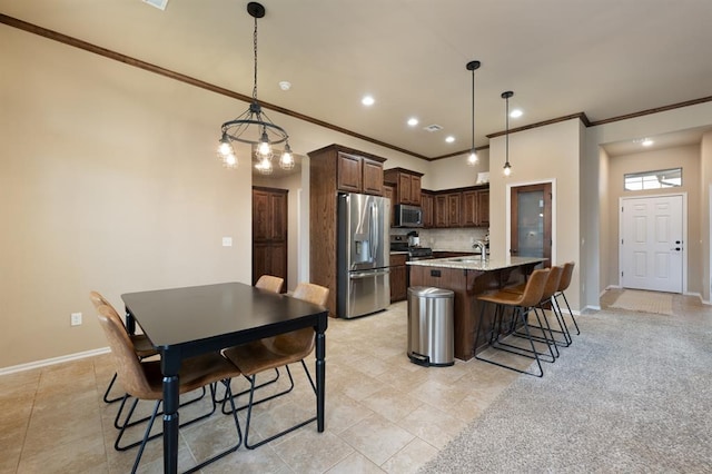 kitchen with appliances with stainless steel finishes, a center island with sink, dark brown cabinetry, a kitchen bar, and decorative light fixtures