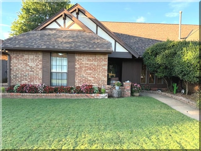 view of front of house with brick siding, a front lawn, and roof with shingles