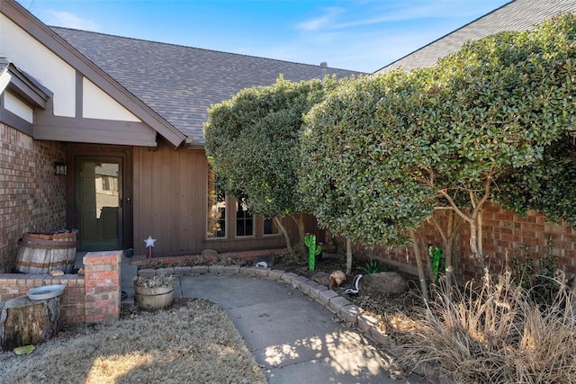 property entrance with brick siding and roof with shingles