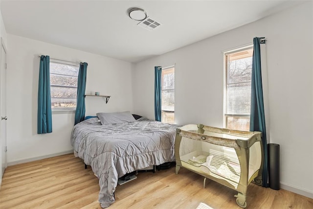 bedroom with hardwood / wood-style flooring and multiple windows