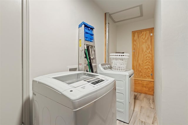 clothes washing area with light hardwood / wood-style floors and separate washer and dryer