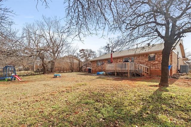 view of yard featuring a trampoline, a wooden deck, and central AC unit