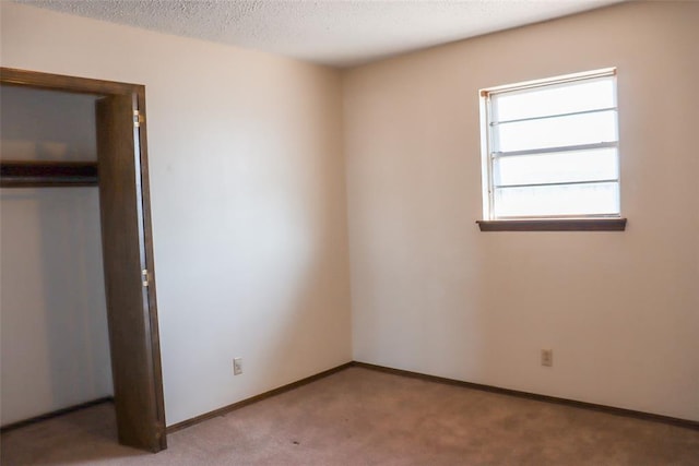 unfurnished bedroom with light colored carpet, a textured ceiling, and a closet