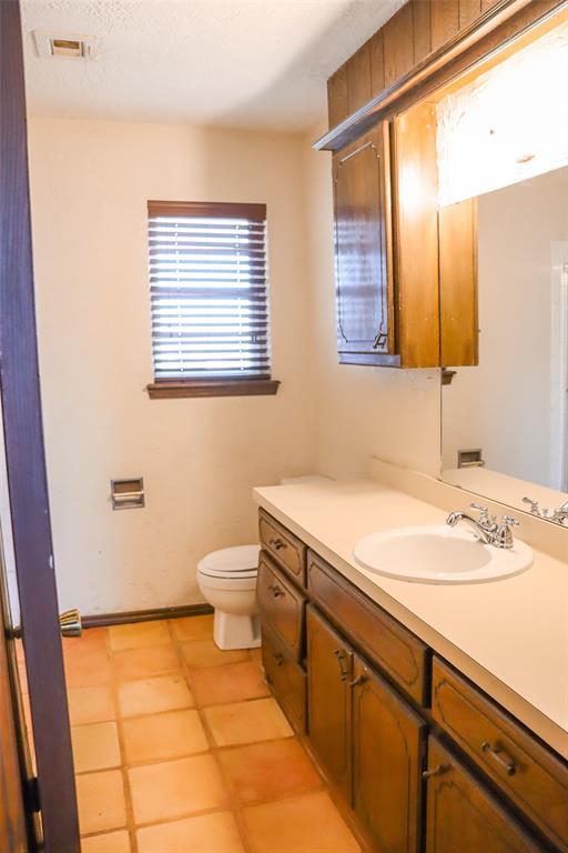 bathroom featuring vanity, a textured ceiling, and toilet