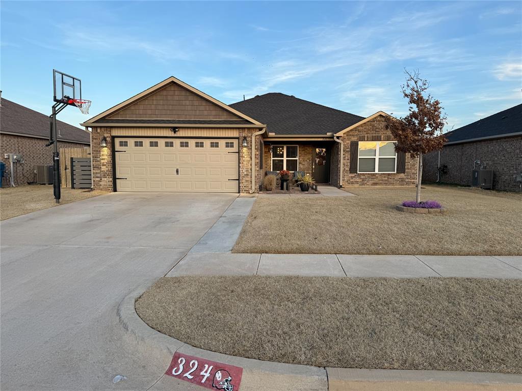 ranch-style home featuring a garage, central AC, and a front yard