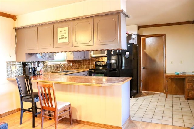 kitchen with a sink, a breakfast bar area, light wood finished floors, black appliances, and a peninsula