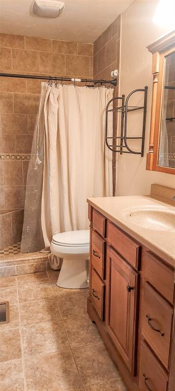 bathroom with visible vents, vanity, toilet, and a stall shower