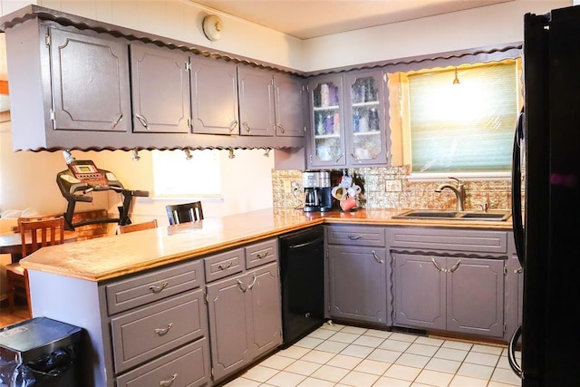 kitchen with a sink, gray cabinetry, light countertops, black appliances, and a peninsula