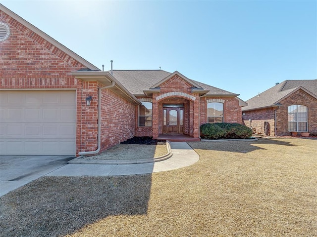 view of front of property featuring a garage, brick siding, a front yard, and a shingled roof