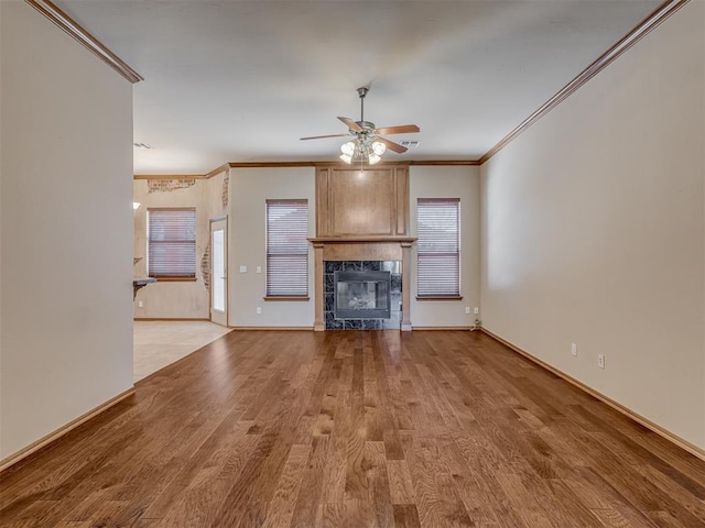 unfurnished living room featuring ornamental molding, light wood-type flooring, a tile fireplace, and baseboards